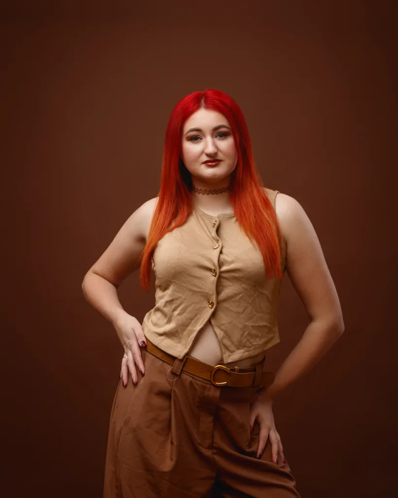 Person with red hair wearing brown outfit posing confidently