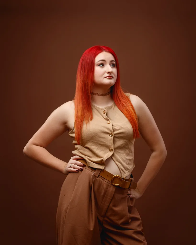 Person with red hair posing against brown background