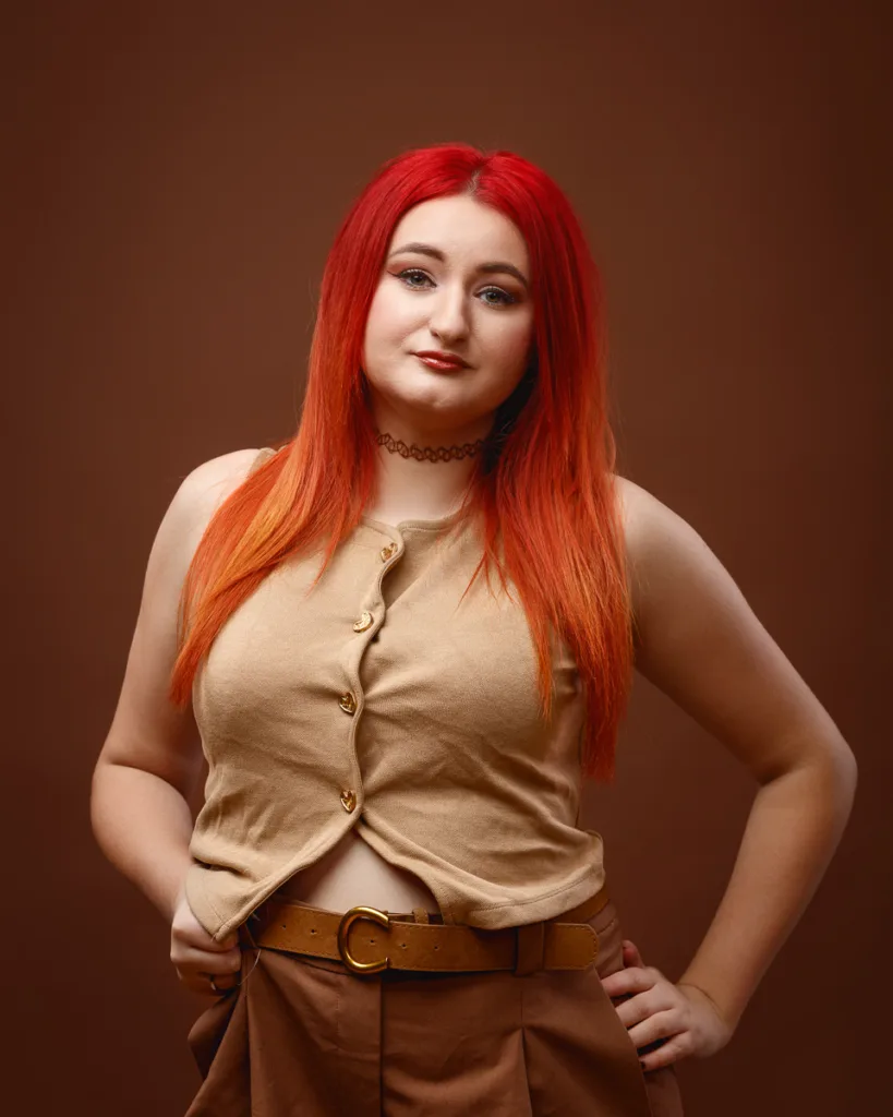 Person with red hair wearing beige outfit posing confidently