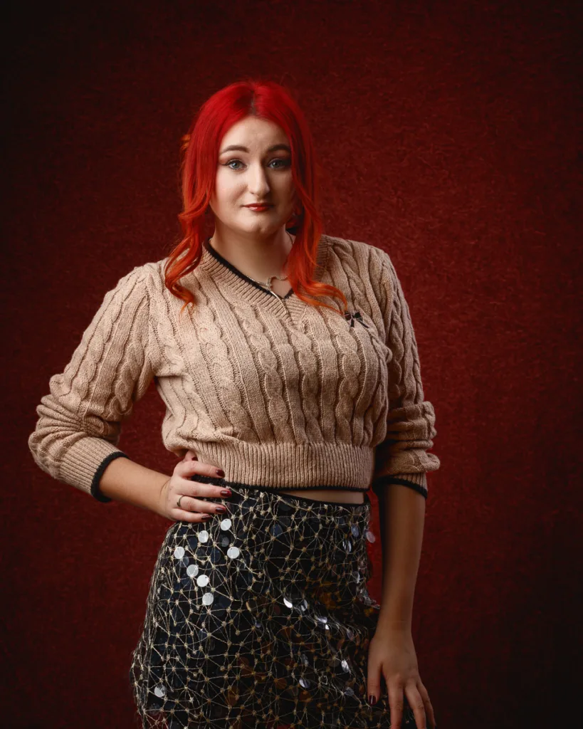 Person with red hair posing against red background