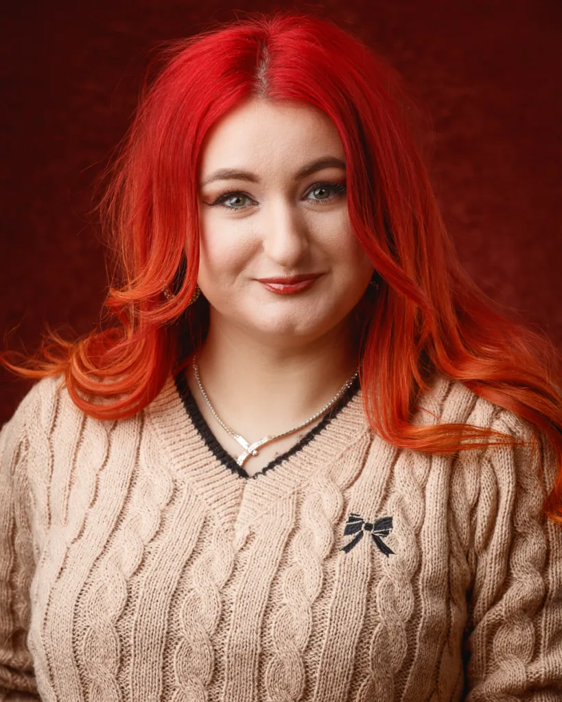 Smiling woman with bright red hair wearing beige jumper