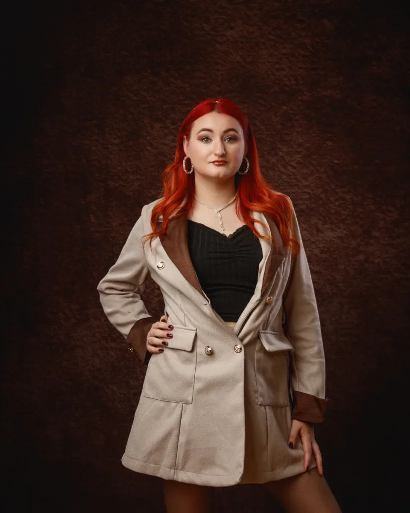 Woman posing in beige coat against dark background
