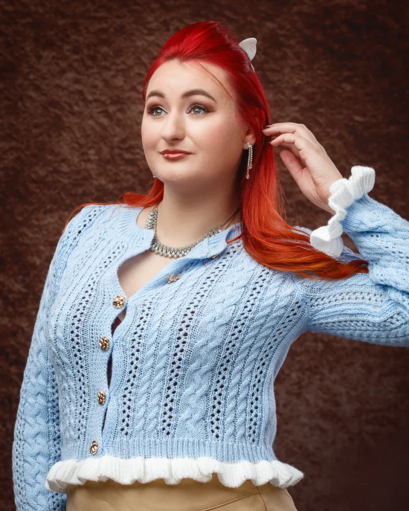 Woman wearing blue knitted cardigan posing confidently