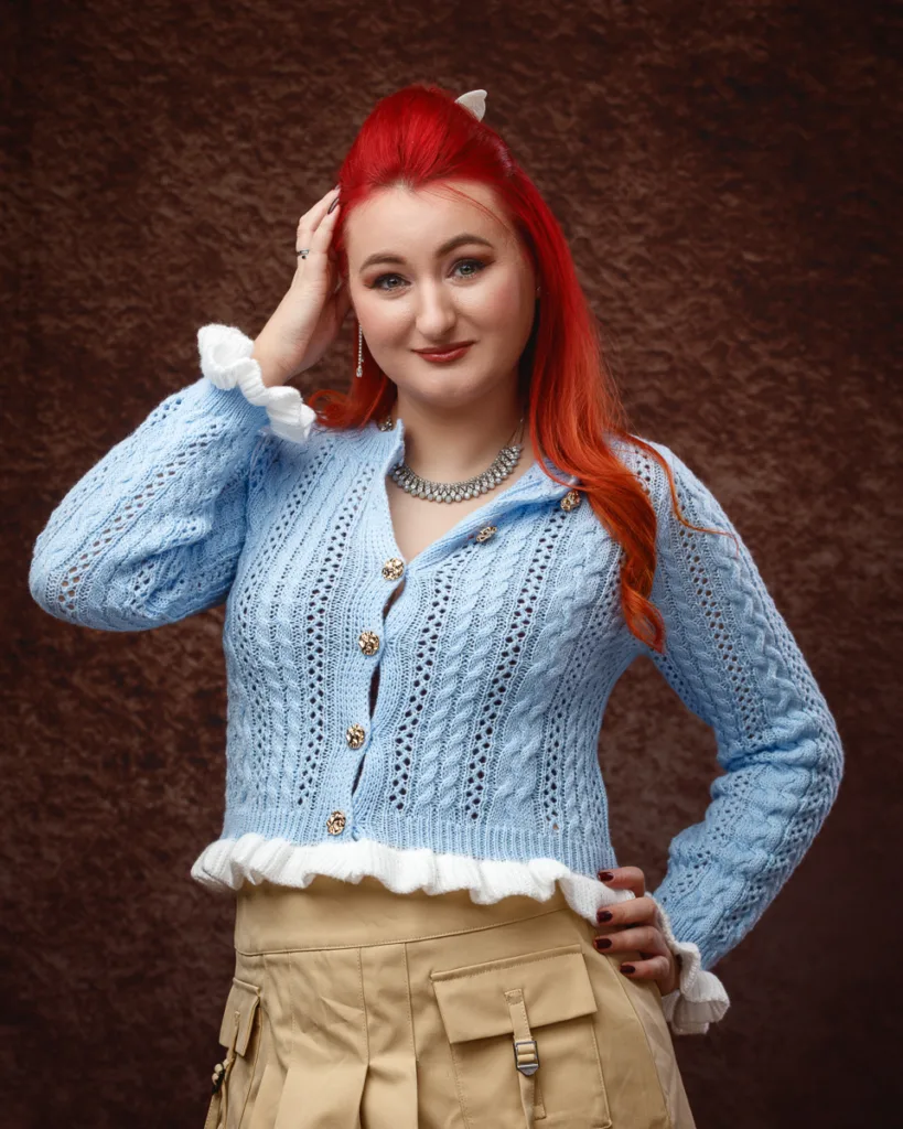 Person wearing blue knit cardigan poses confidently indoors