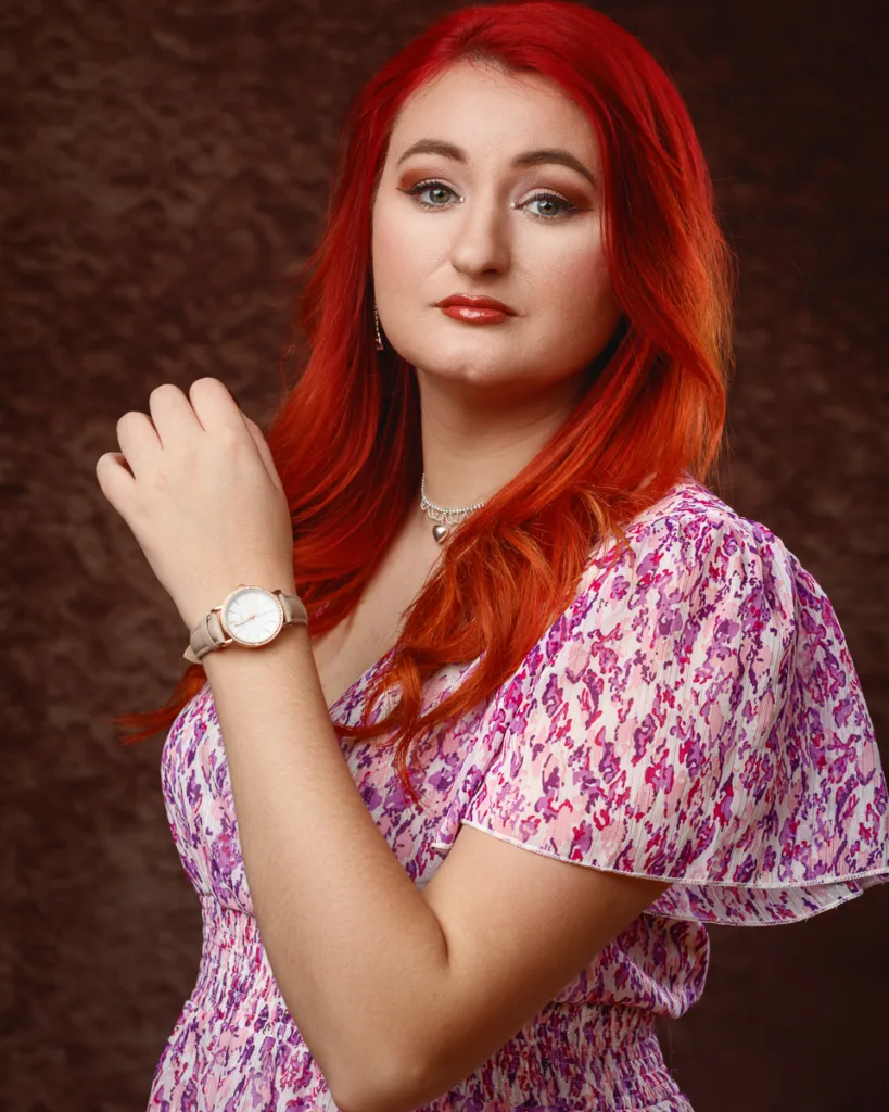 Person with red hair wearing floral dress and watch