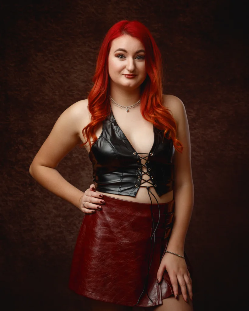 Woman with red hair in leather outfit posing confidently