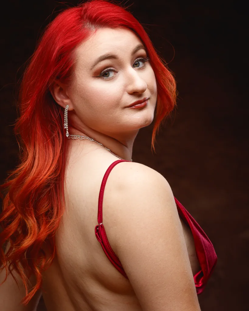 Woman with red hair wearing red dress posing confidently