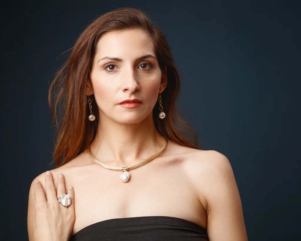 Woman wearing elegant pearl jewellery, serious expression.
