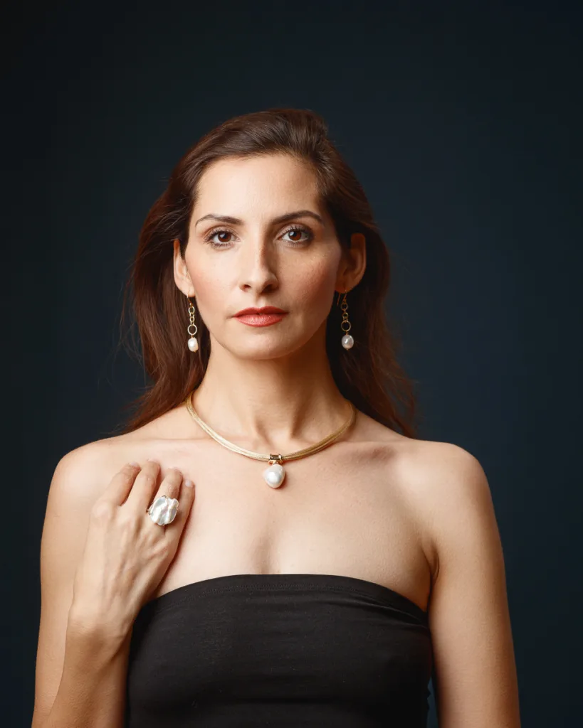 Woman wearing pearl jewellery against dark background.