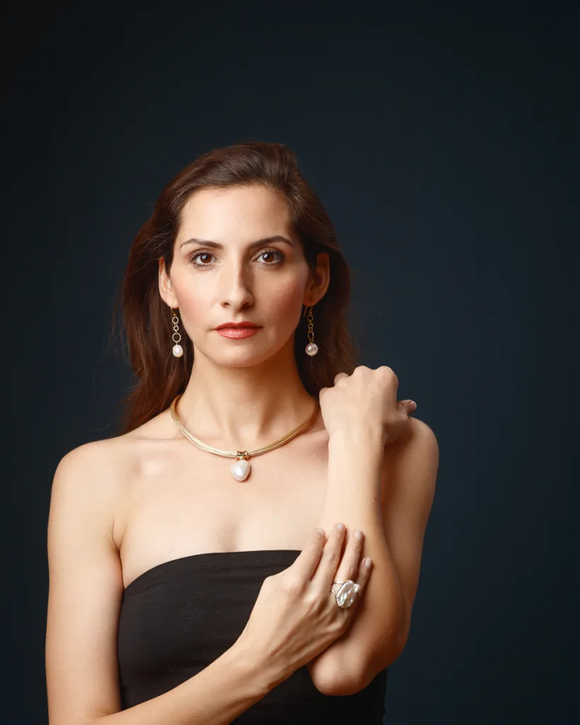 Woman wearing elegant pearl jewellery against dark background.