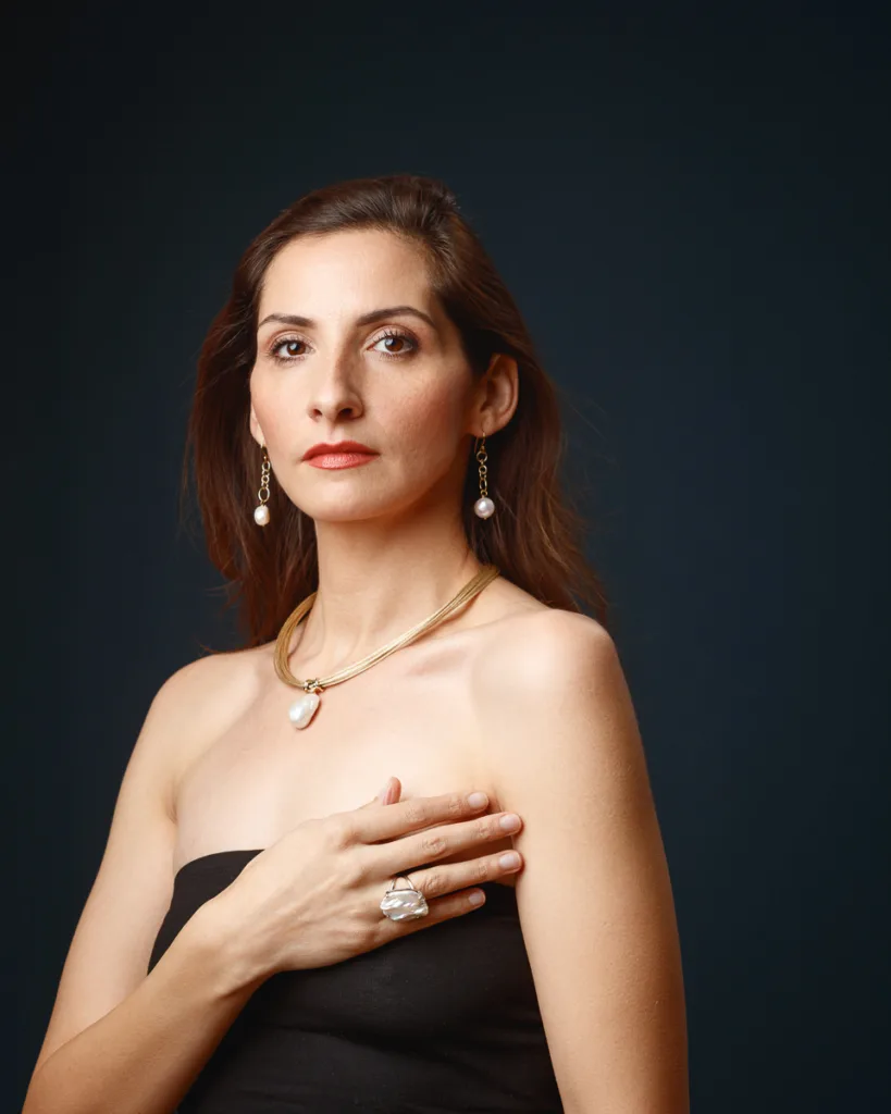 Woman wearing pearl jewellery on dark background.