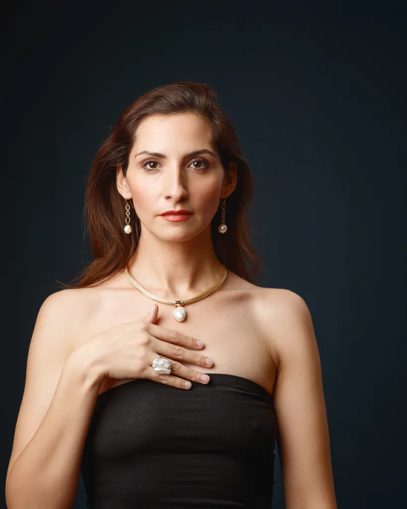 Woman with pearl jewellery against dark background.
