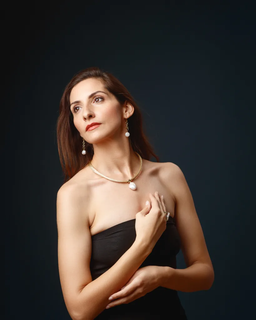Woman in elegant black dress with pearl necklace.