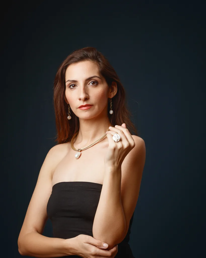 Woman wearing elegant jewellery against dark background.