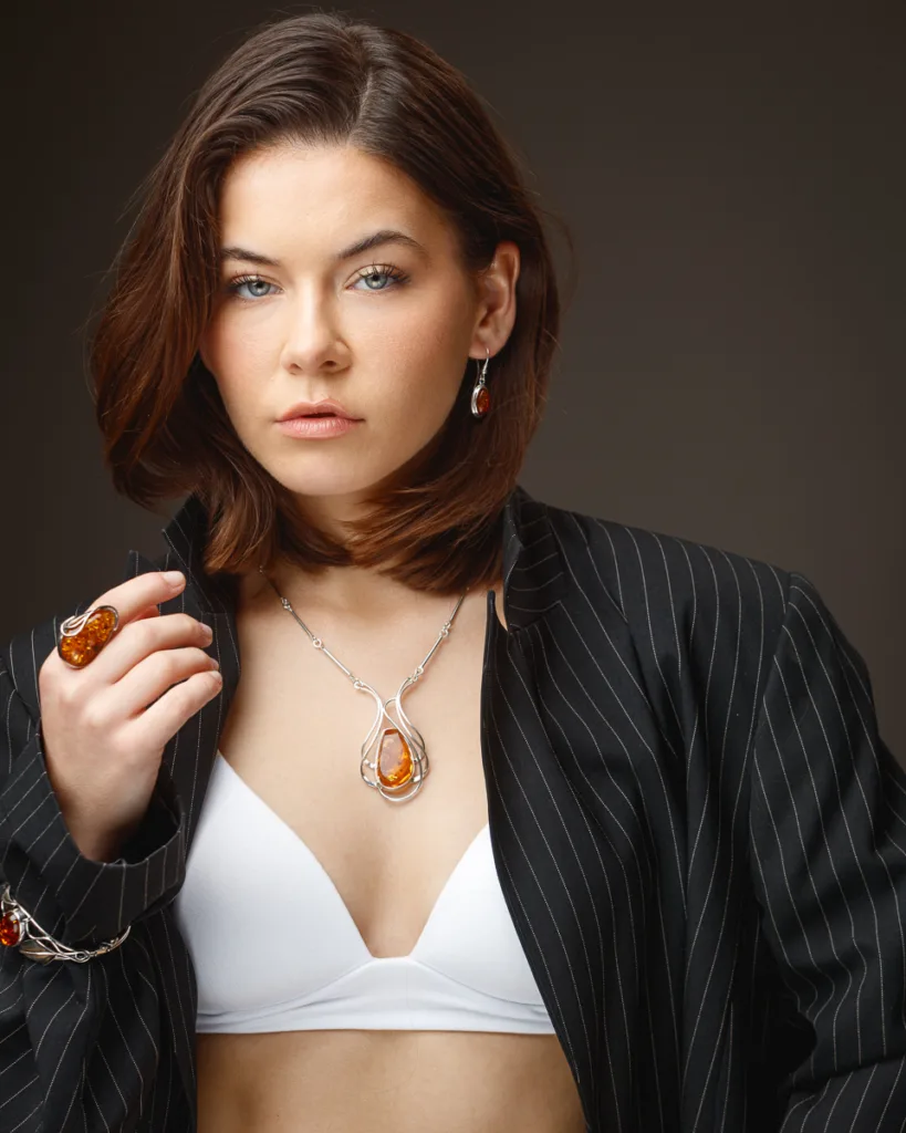 Woman wearing amber jewellery and striped blazer.