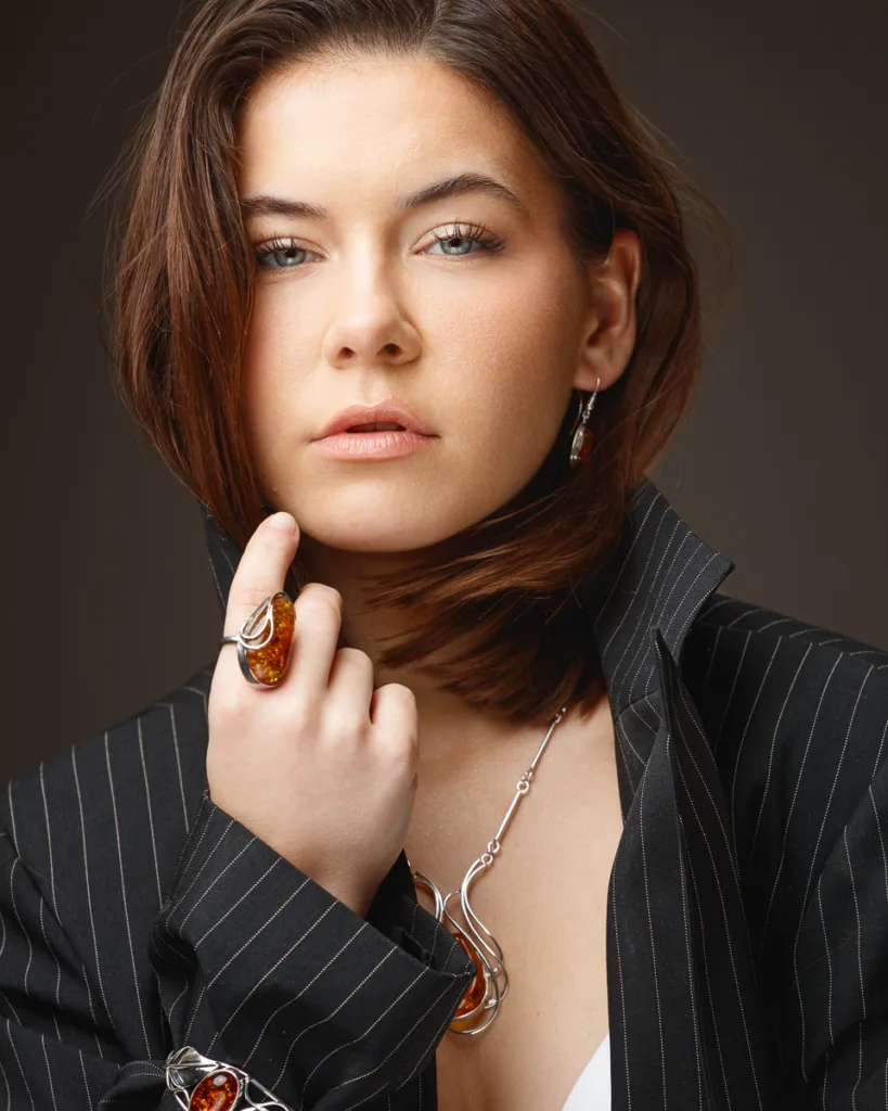 Woman wearing jewellery and pinstripe jacket, close-up portrait.