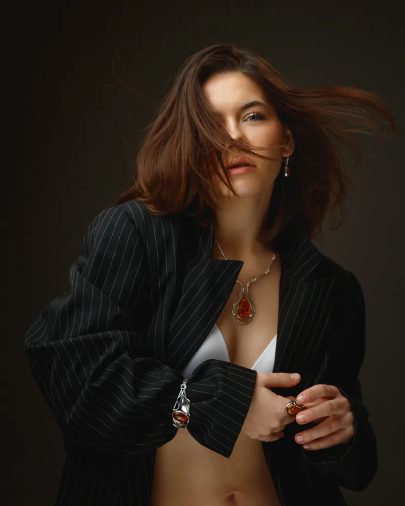 Woman in black blazer, artistic jewellery display.