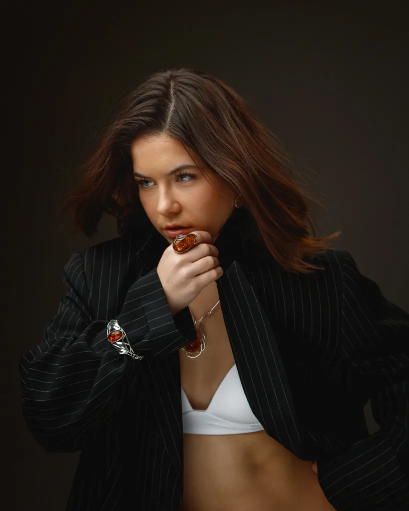 Woman in pinstripe suit and white top poses thoughtfully.
