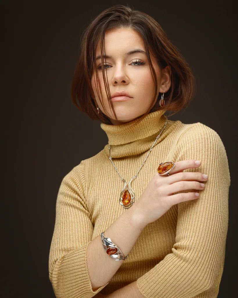Woman wearing amber jewellery, beige turtleneck.