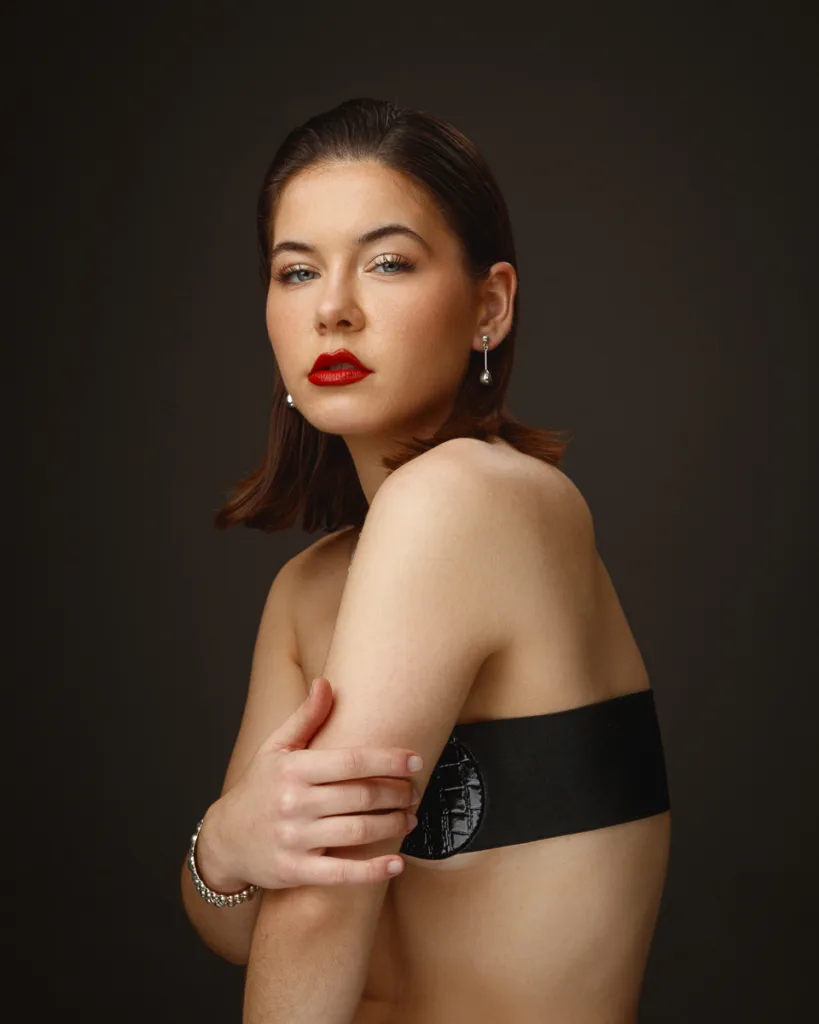 Woman with red lipstick and pearl earrings posing.