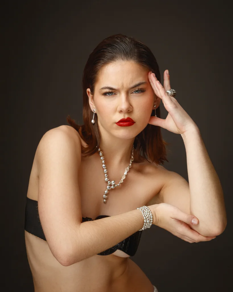 Woman with jewellery posing against dark background.
