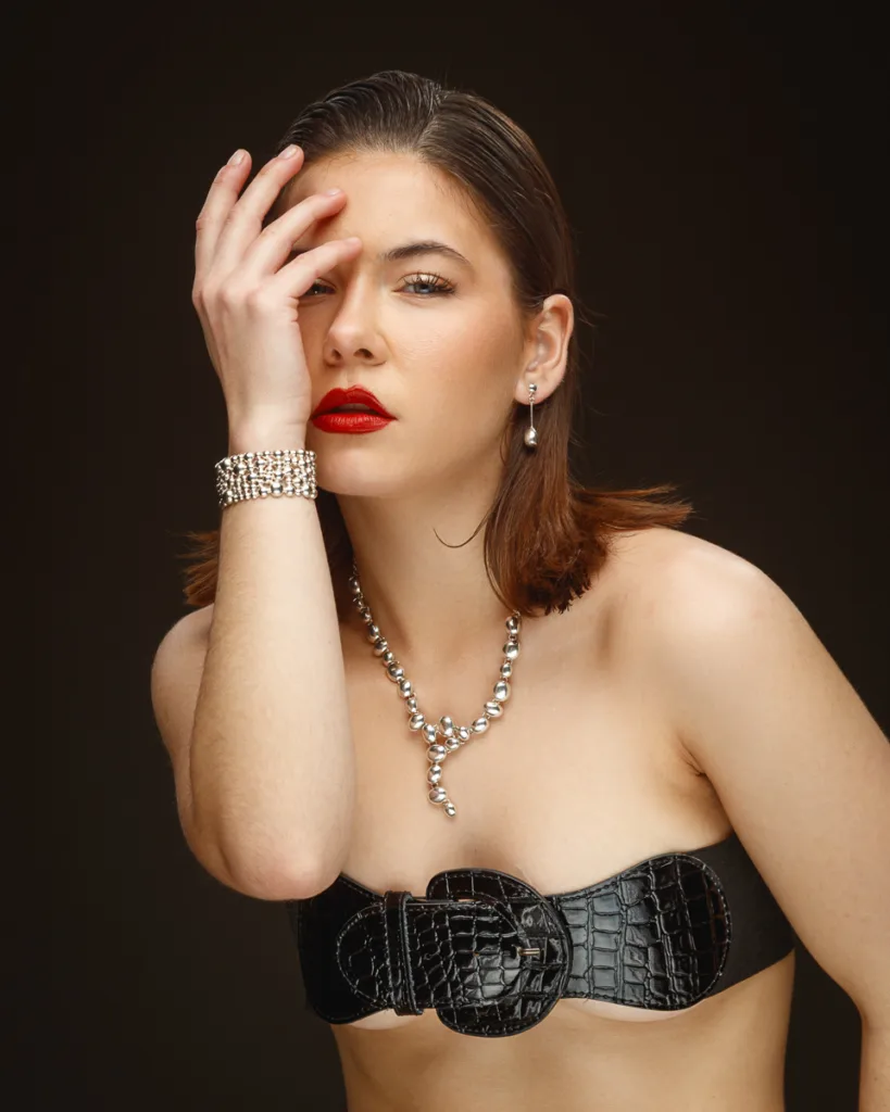 Model with jewellery and black top poses elegantly.