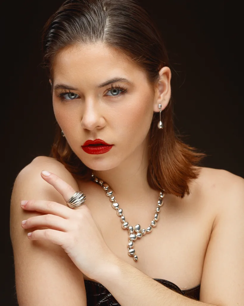 Woman with jewellery and red lipstick posing elegantly.