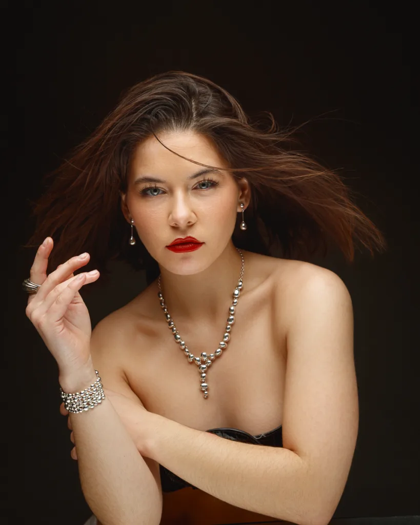 Woman in elegant jewellery, posing confidently.