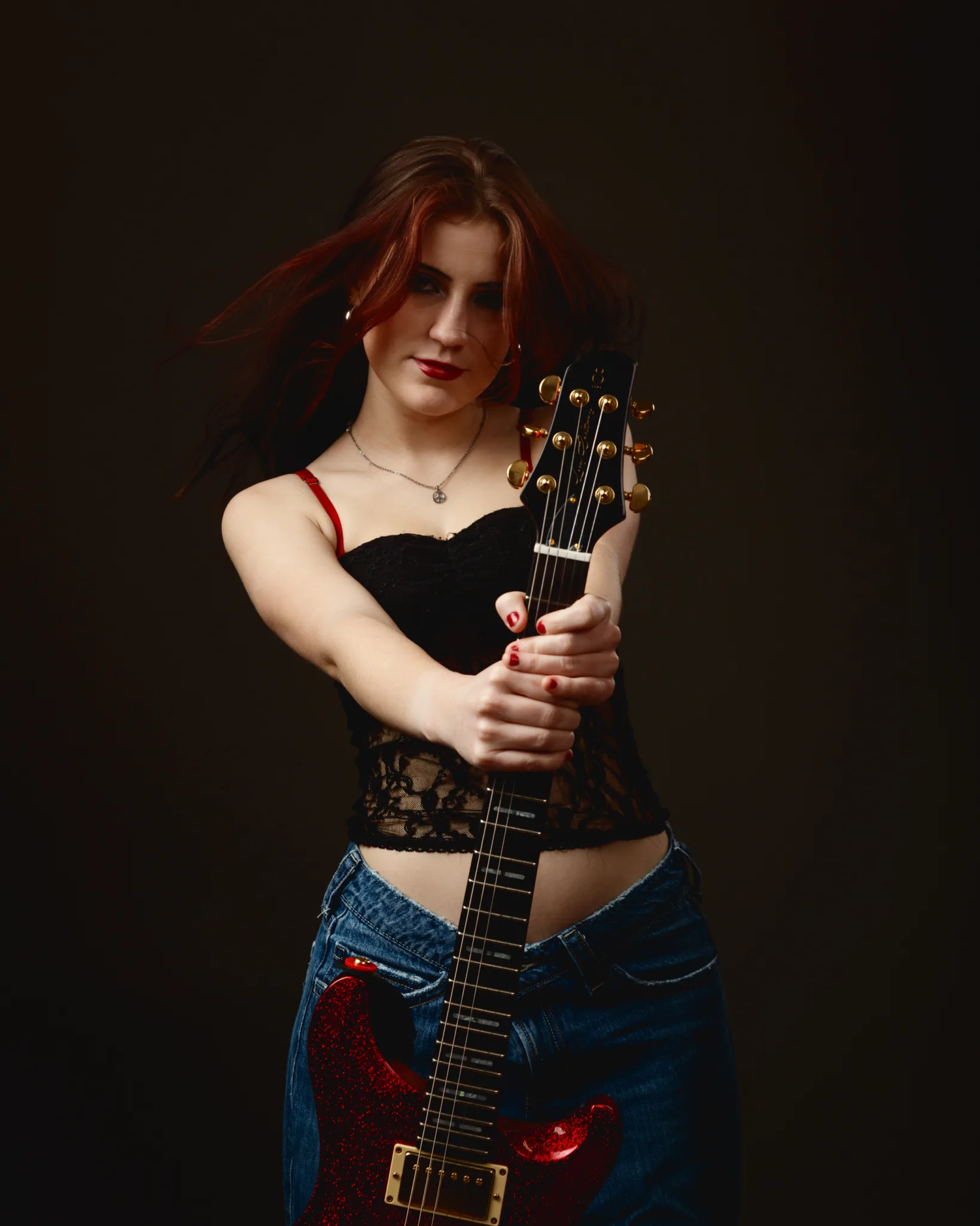 Woman holding electric guitar in stylish outfit.