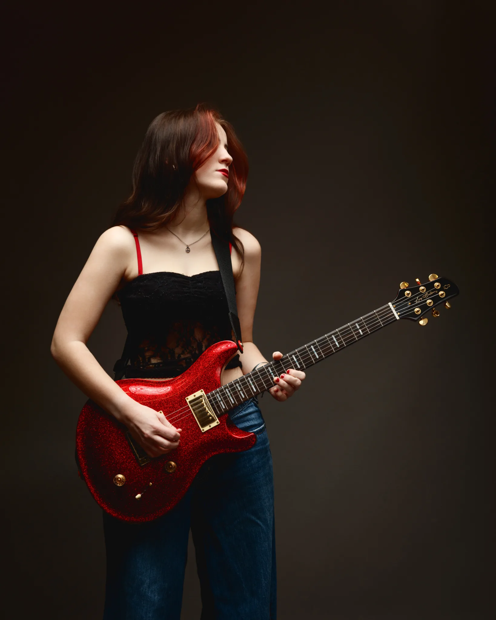 Woman playing a sparkling red electric guitar.