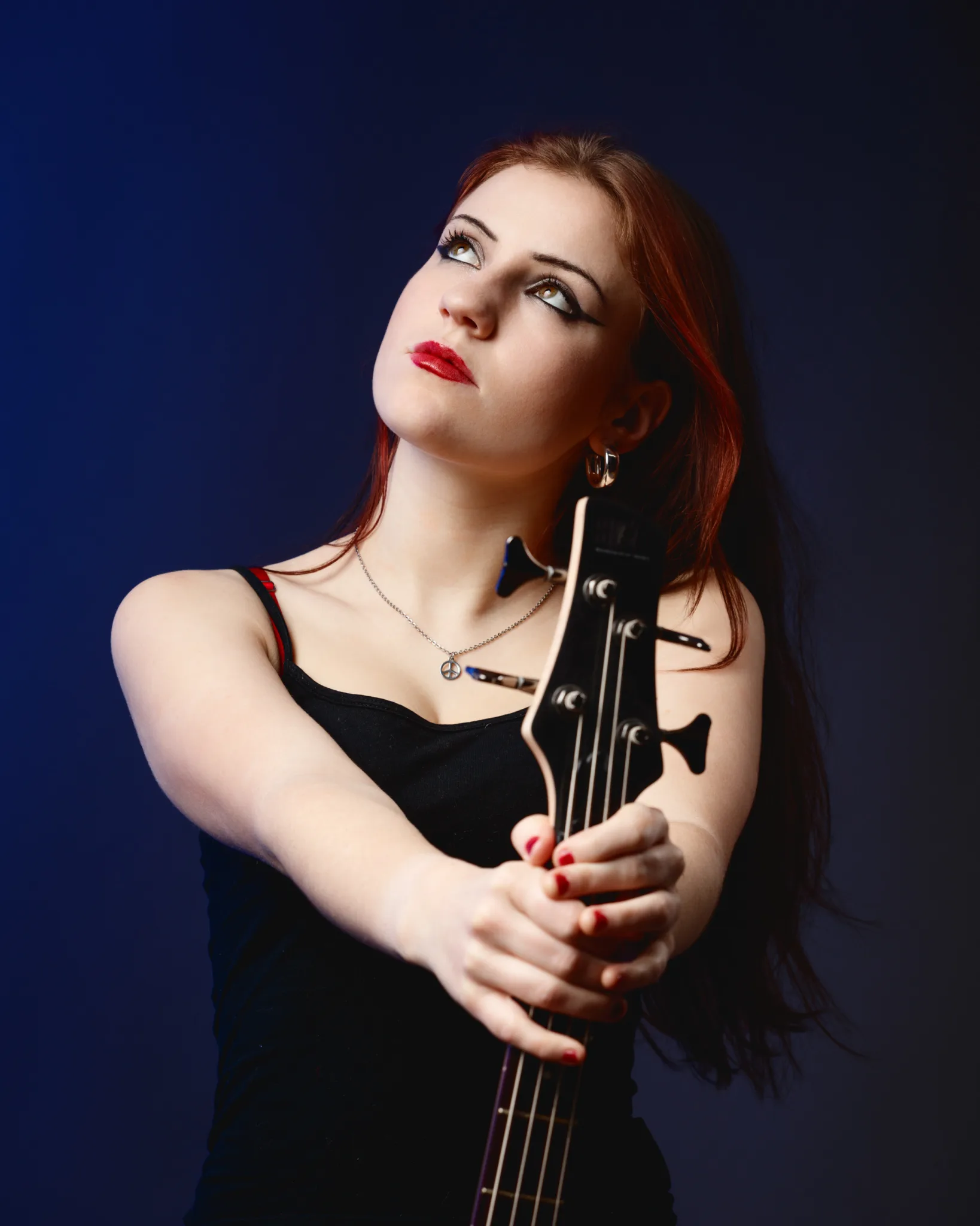 Woman holding electric guitar, looking upwards.
