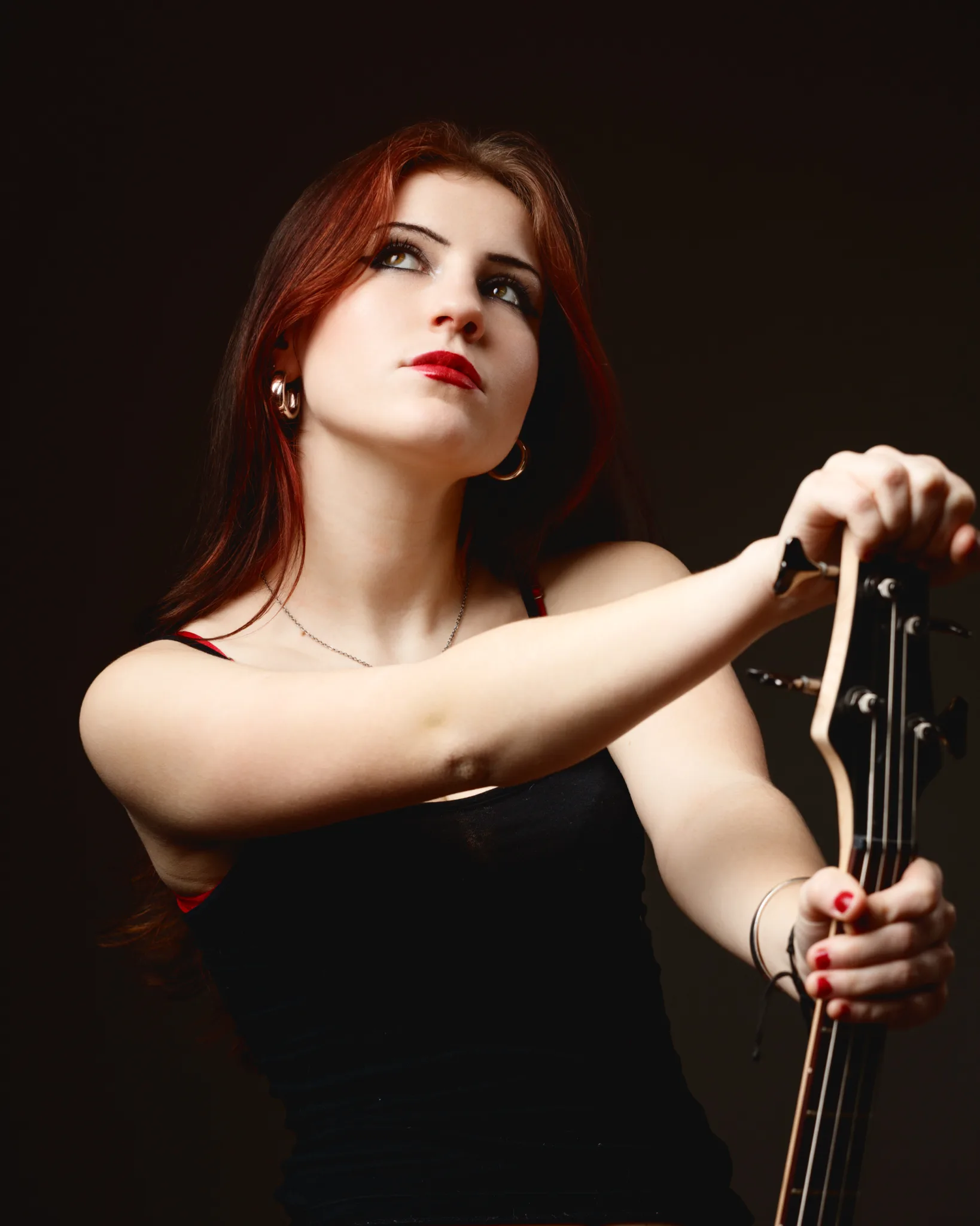 Woman holding a guitar, looking contemplative.