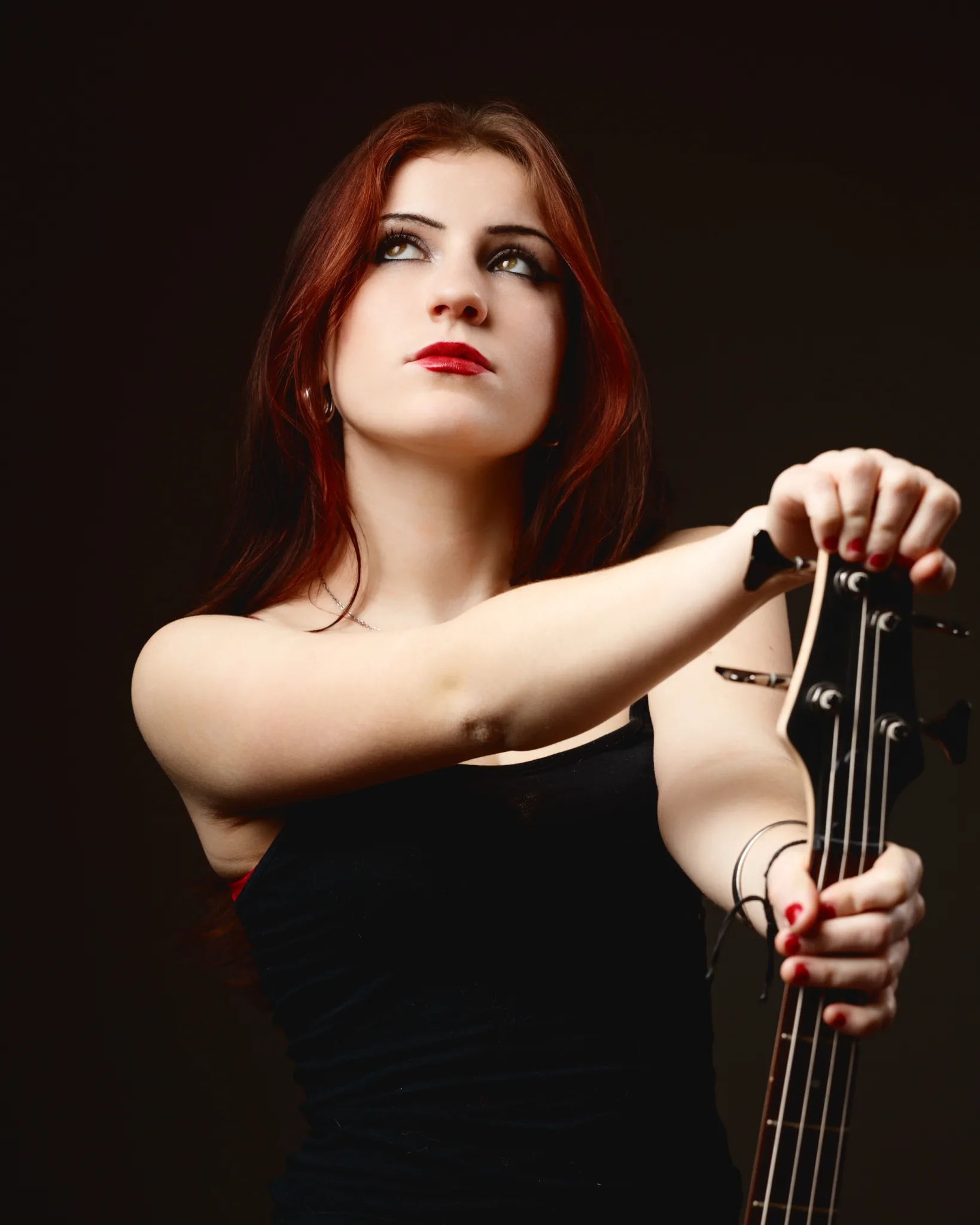 Woman holding a guitar, looking upwards.