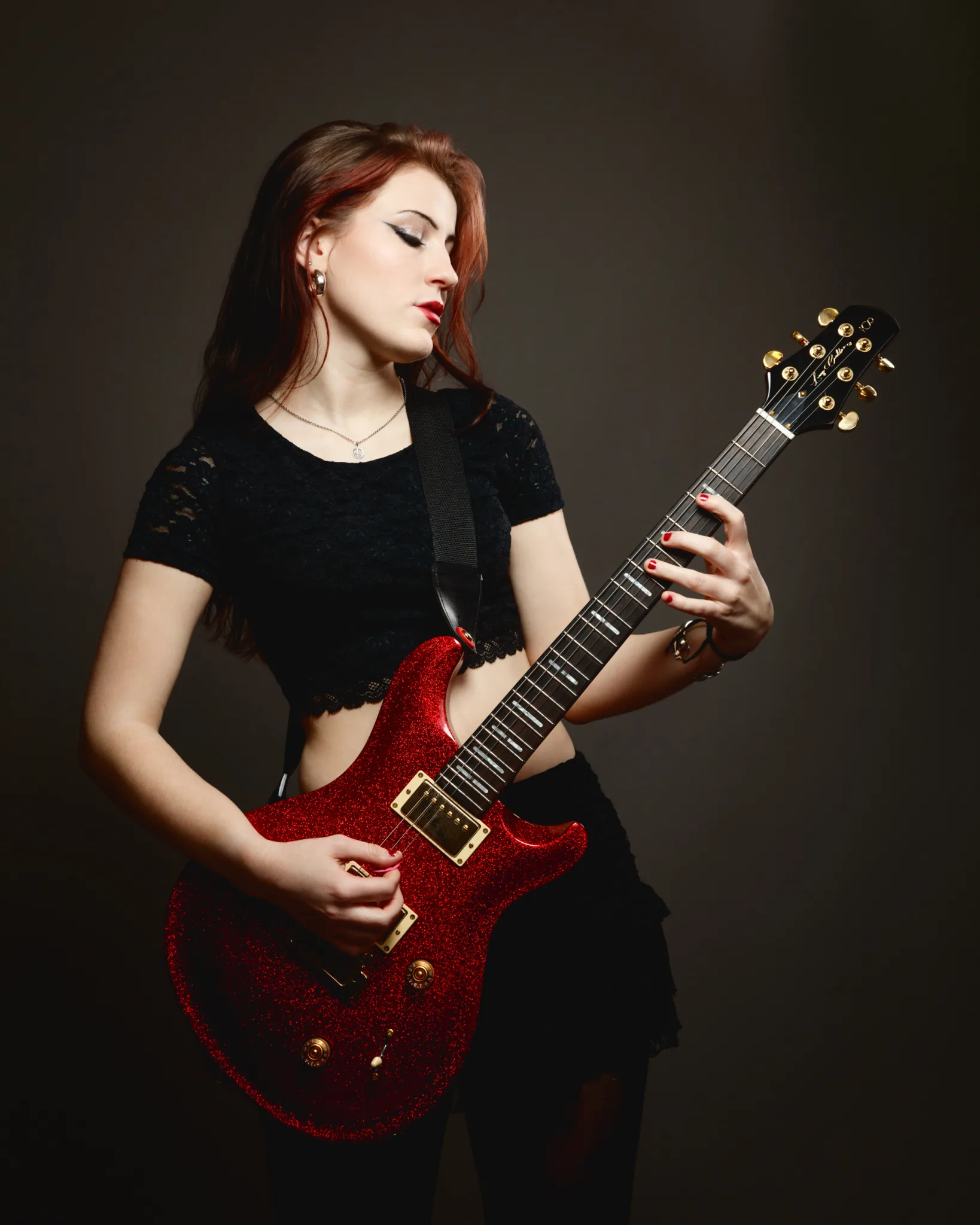 Woman playing red electric guitar passionately.