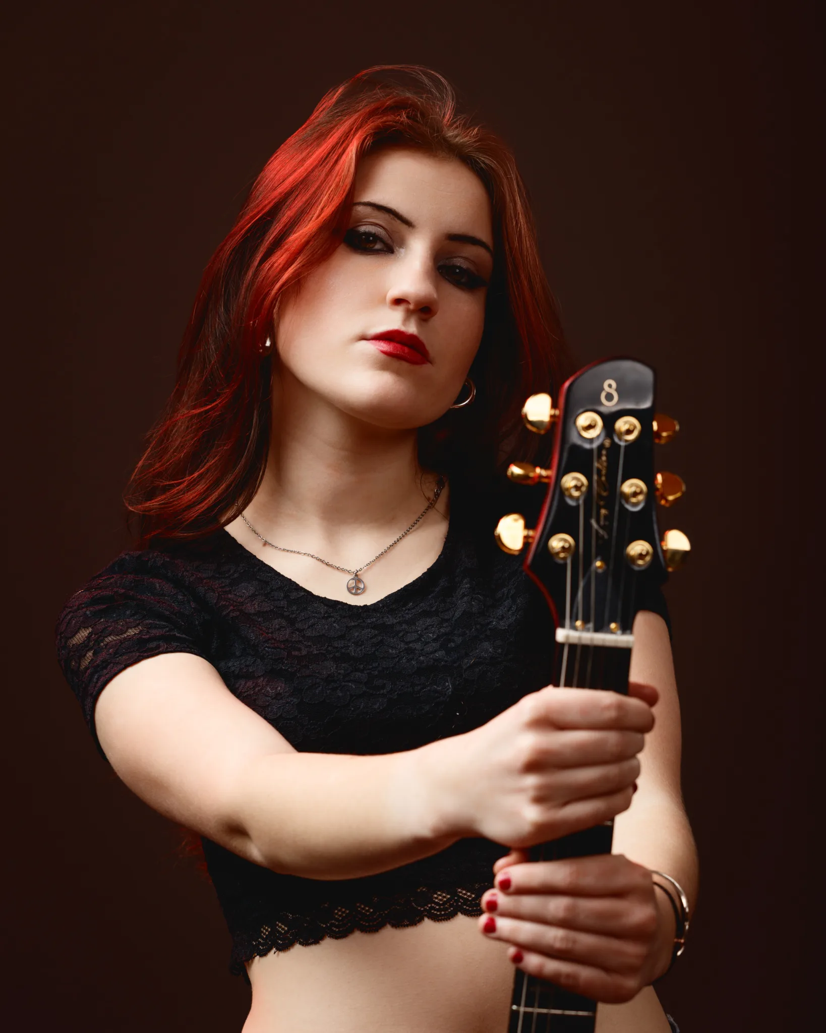 Woman holding a guitar, looking confidently forward.