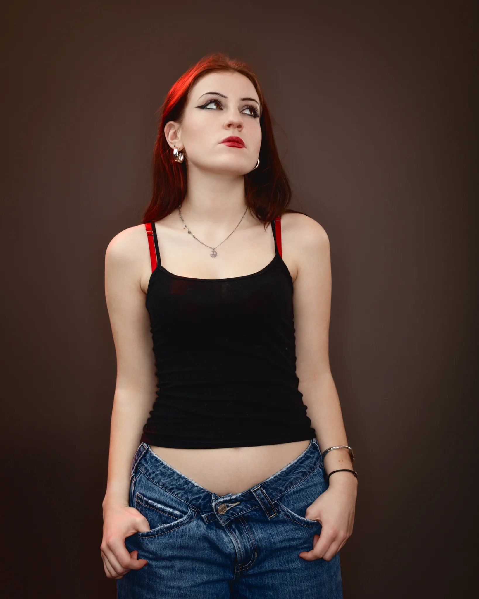 Person in black top and blue jeans, thoughtful expression.